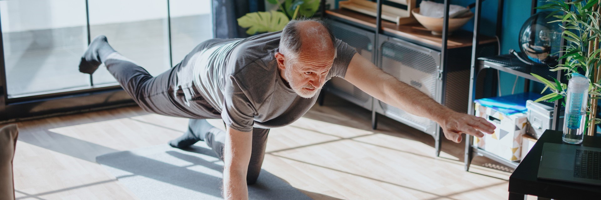 Older man doing yoga in living room