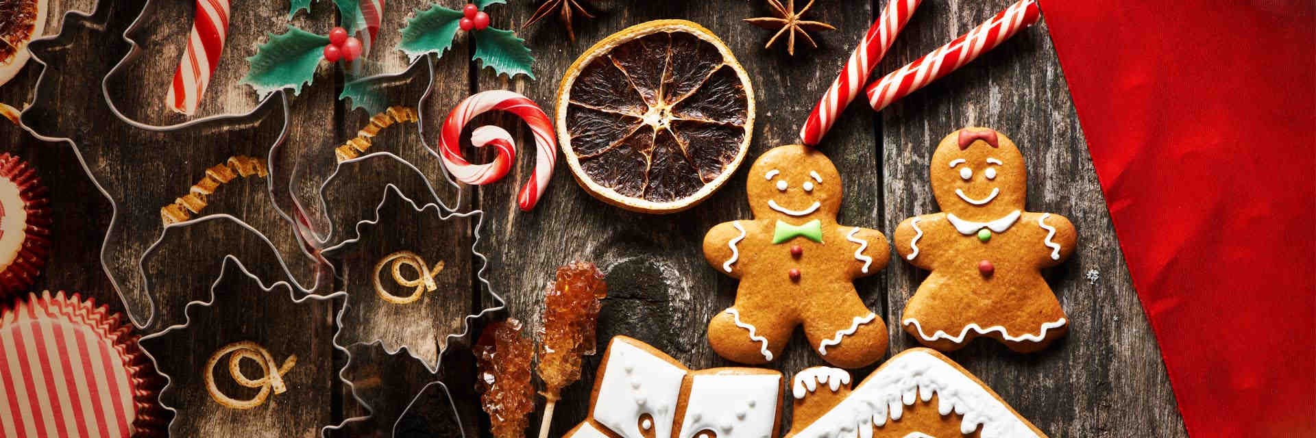 Gingerbread people, candy canes and holly on a wooden table