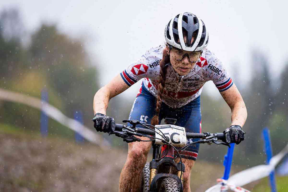 Woman racing mountain bike covered in mud
